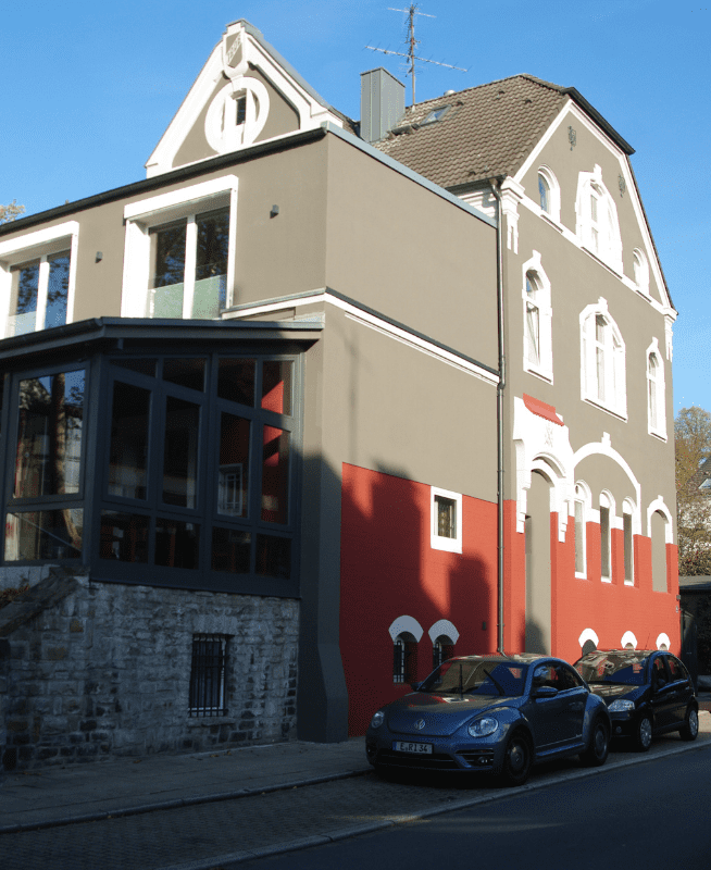 Mehrfarbiger Anstrich eines Wohnhauses mit Gewerbeanteil, professionell ausgeführt von Malerbetrieb Rickers, verleiht dem Gebäude ein lebendiges und individuelles Erscheinungsbild